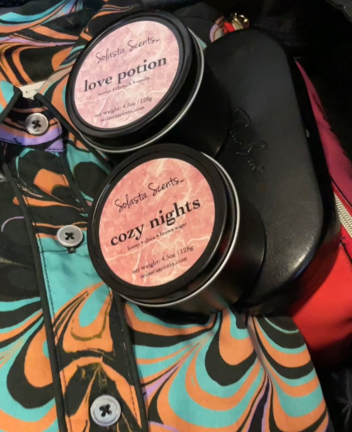 Solasta Scents® travel candles in a suitcase with beautiful clothes.